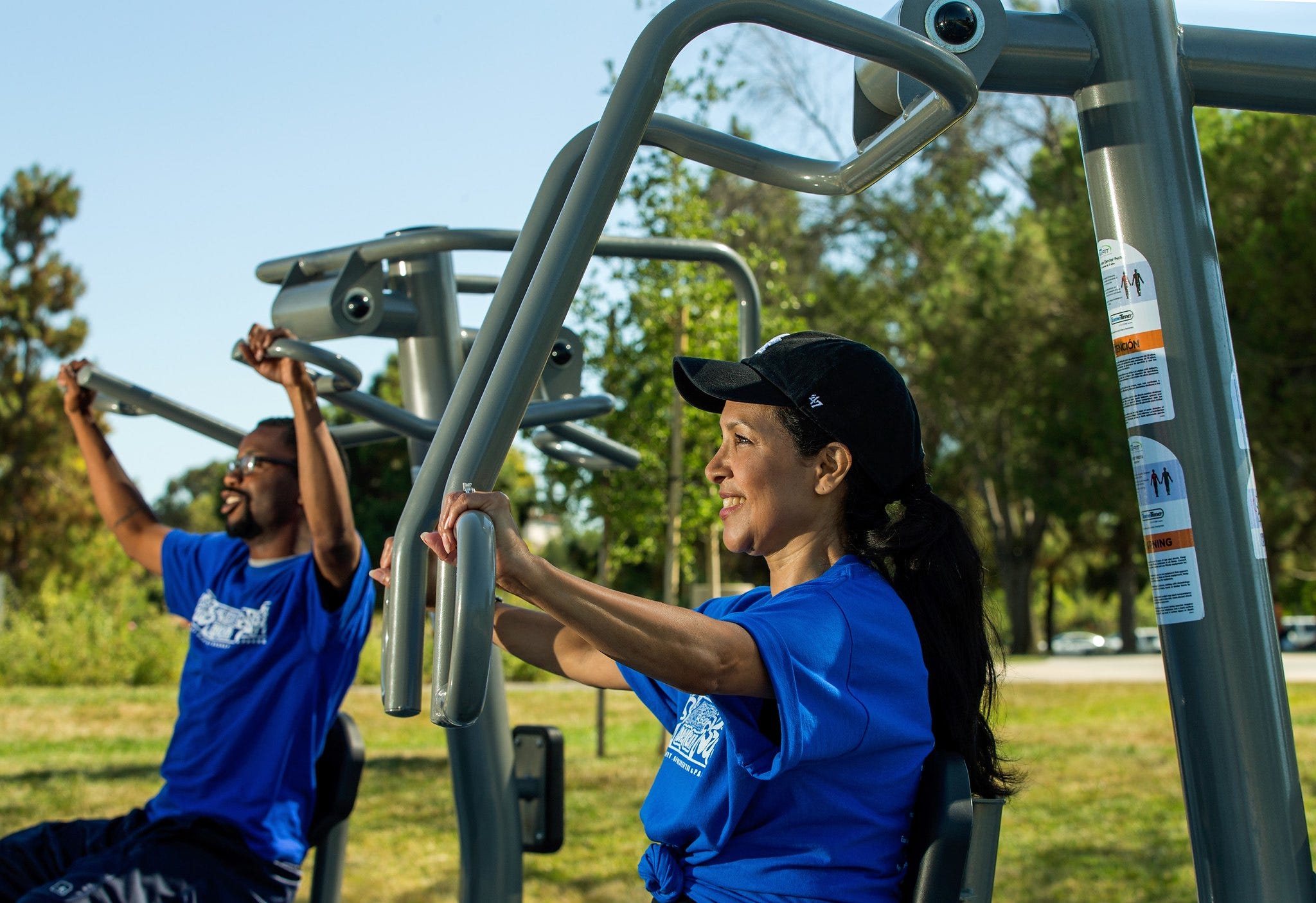 People using outdoor fitness equipment in a park
