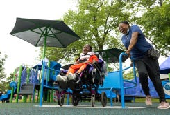 Mother pushes daughter on an inclusive merry go round 