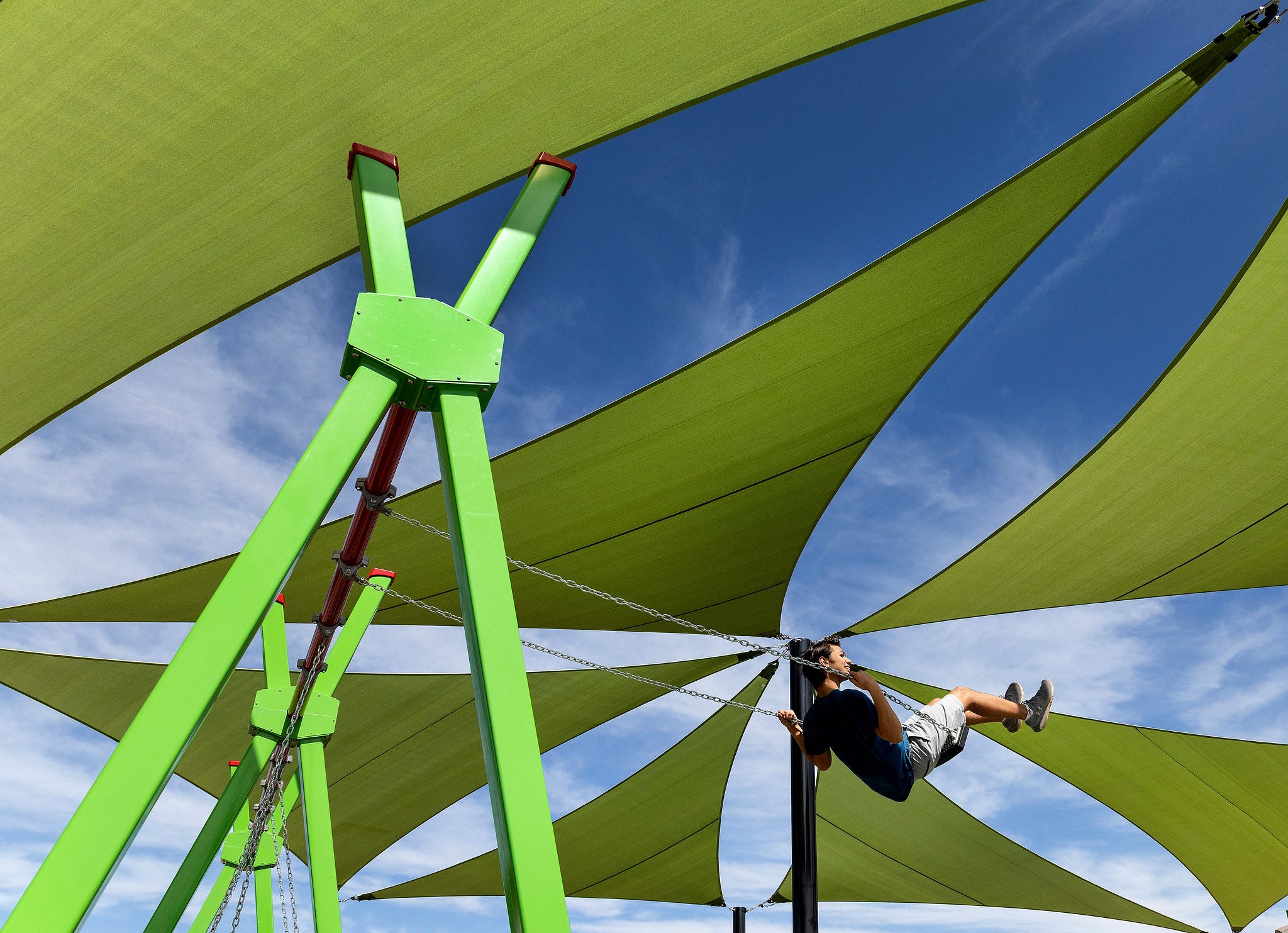 Child swinging in front of playground shade