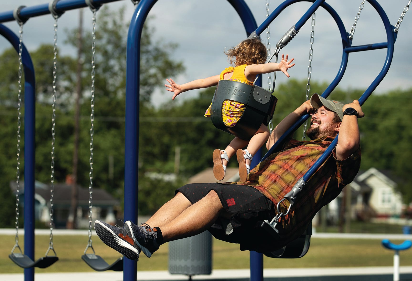 Father and child swinging while facing each other in opposing swings