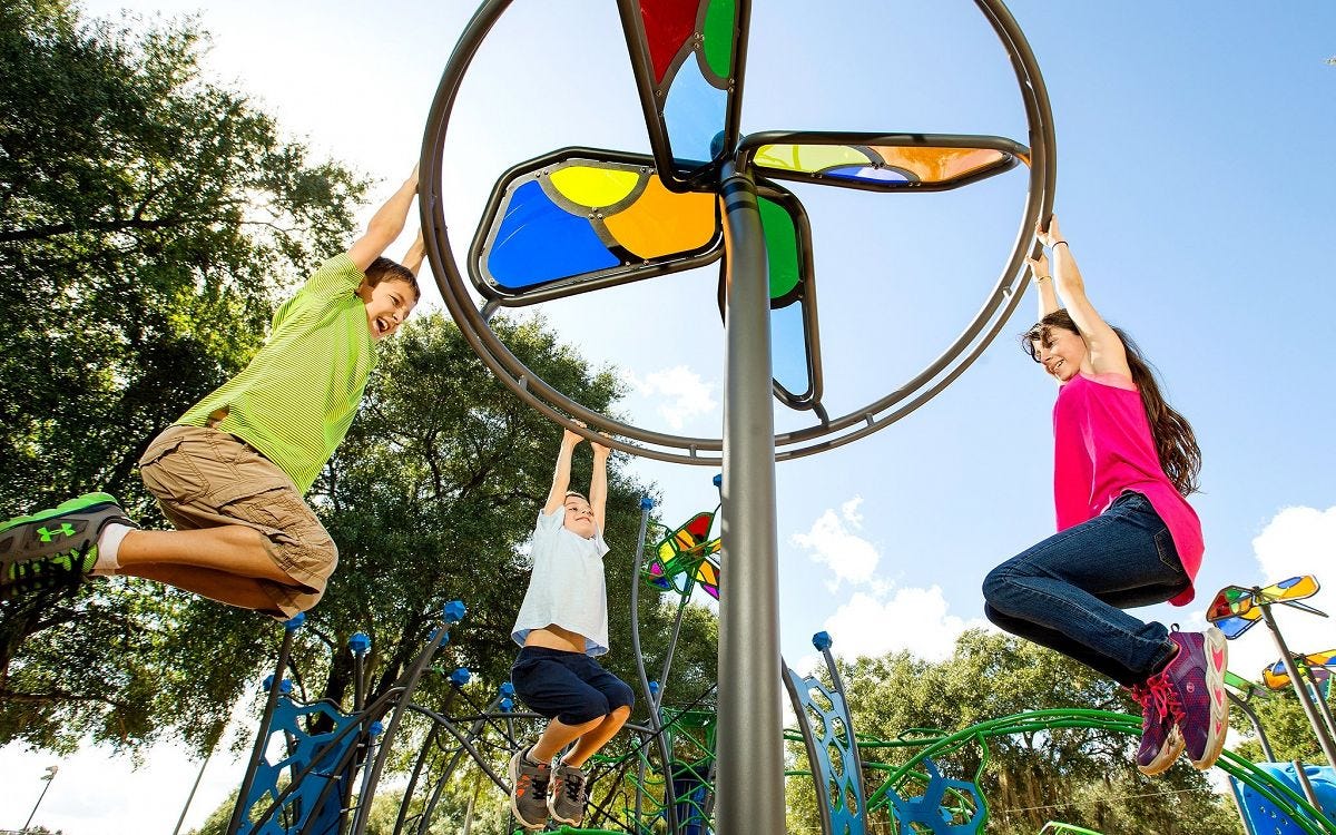 Children playing on a spinning mechanism with an overhead that looks like stained glass