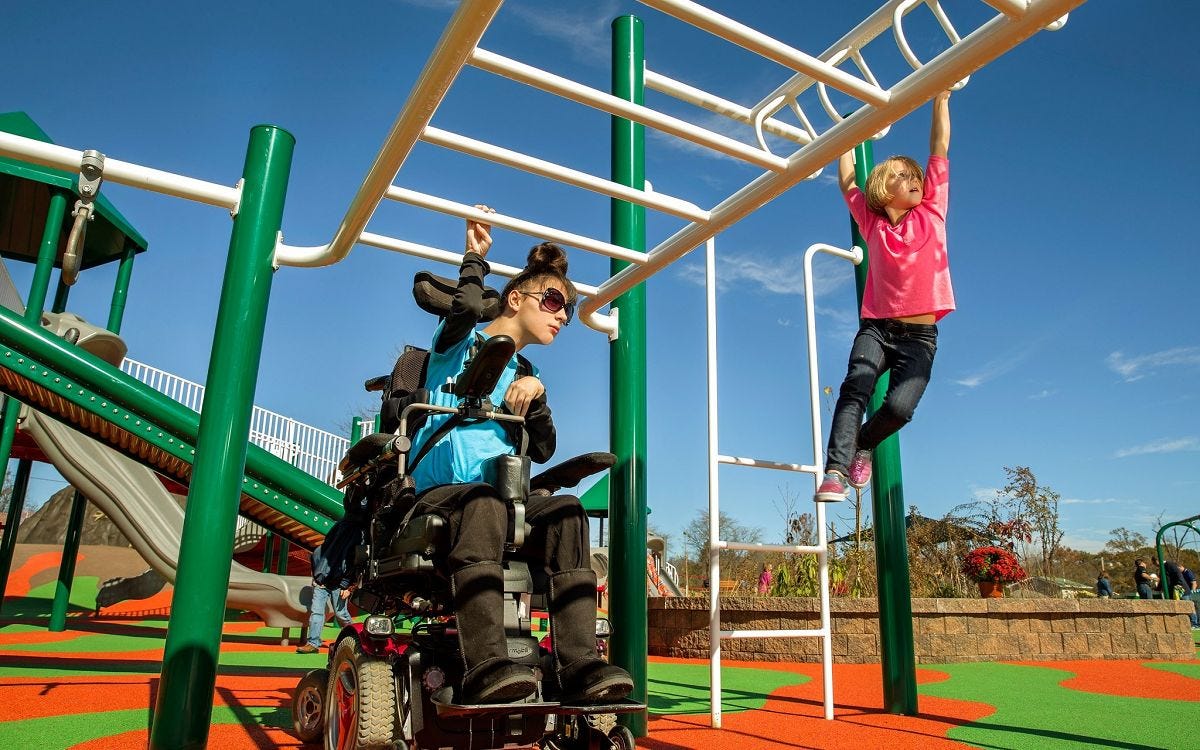 Child using a mobility device using an overhead climber alongside another child