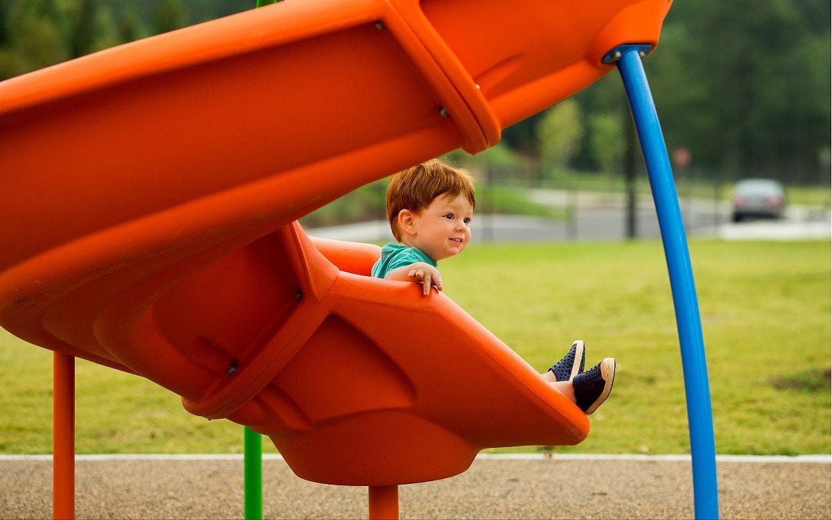 Spiral Slides by GameTime Child sitting at the bottom of a spiral slide