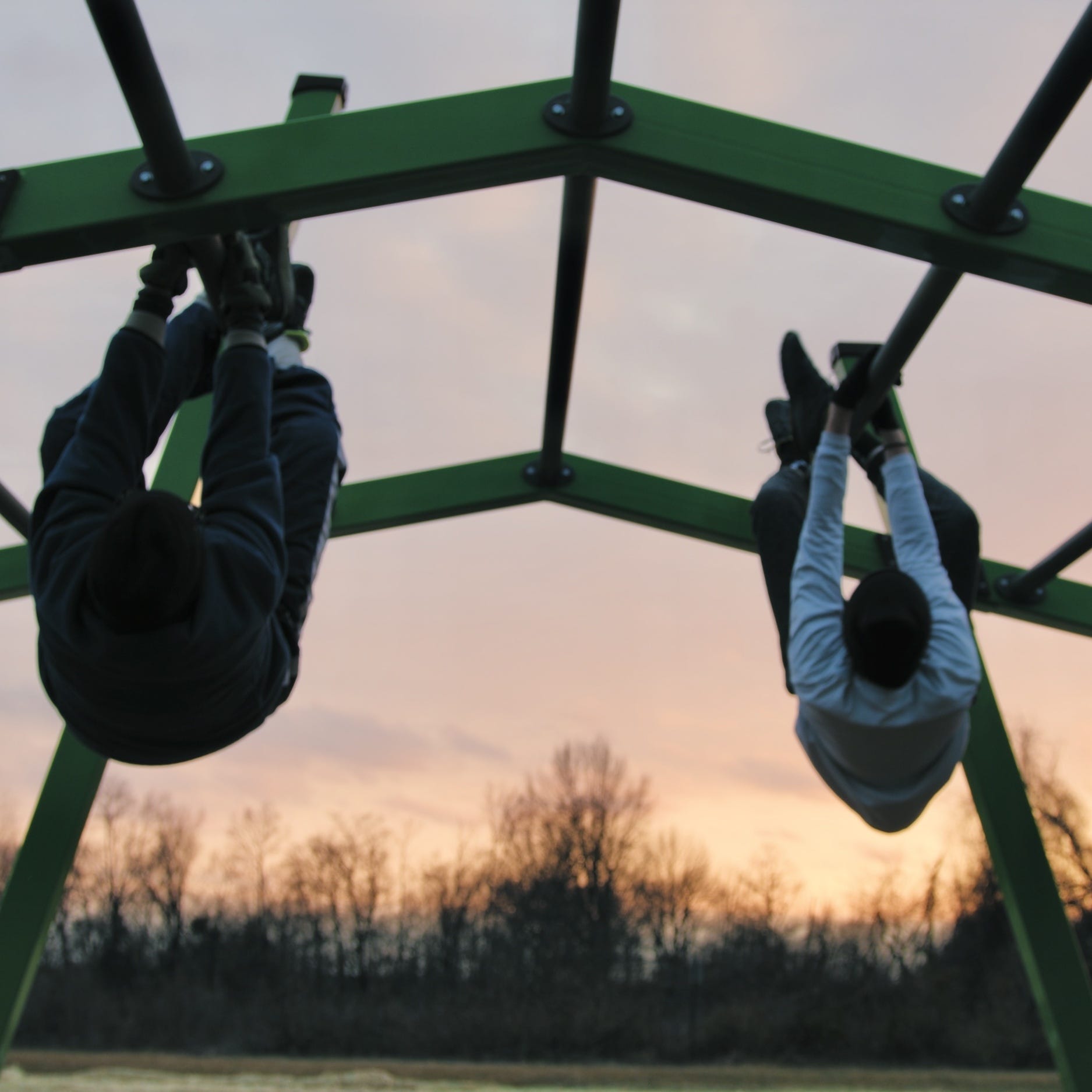Adults hanging from an overhead climber