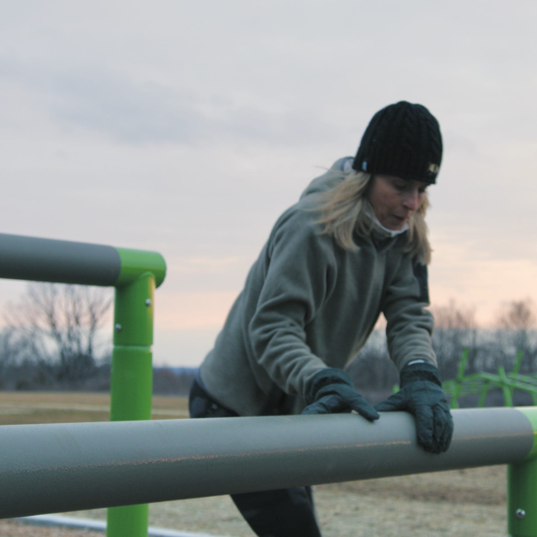 Woman climbing over a pole